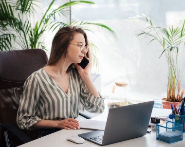 Ofisindeki bilgisayarda çalışan genç bir kadın.