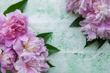 Pembe şakayıklı çiçek çerçevesi. Yeşil ahşap arka planda pembe çiçekler. Uzayı kopyala, üst görünüm. Anneler Günü, Sevgililer Günü, Doğum günü konsepti.