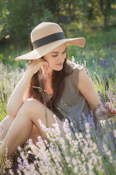 Beautiful young woman on lavender field. Sunset. Attractive young female outdoors.