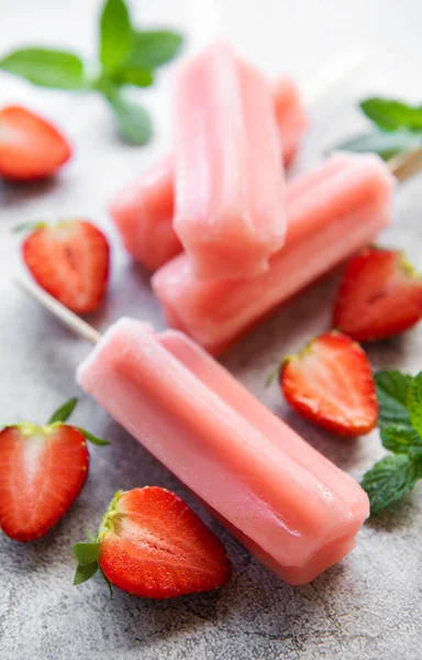 Homemade frozen strawberry ice cream popsicles and fresh strawberries on a concrete background. Summer dessert