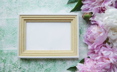 Güzel çiçek kompozisyonu. Mesaj için boş çerçeve, yeşil ahşap arka planda pembe şakayıklar. Düz konum, üst görünüm, kopyalama alanı