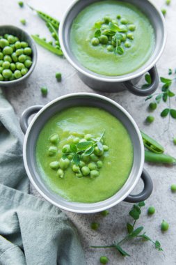 Fresh green pea soup bowl on gray concrete background