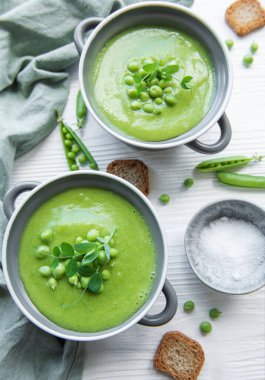 Fresh green pea soup bowl on gray concrete background