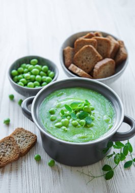 Fresh green pea soup bowl on gray concrete background