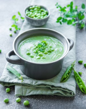 Fresh green pea soup bowl on gray concrete background