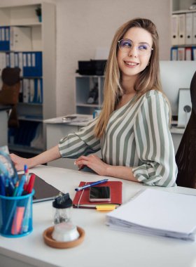 Ofisindeki bilgisayarda çalışan genç bir kadın.