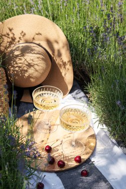 Summer picnic on a lavender field with champagne glasses and cherry berries