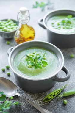 Fresh green pea soup bowl on gray concrete background