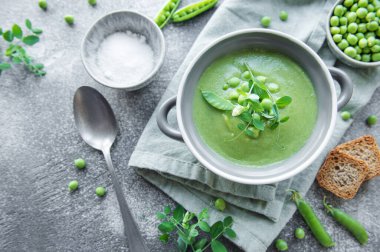 Fresh green pea soup bowl on gray concrete background