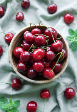 Fresh red cherries fruit in bowl on a green textile background