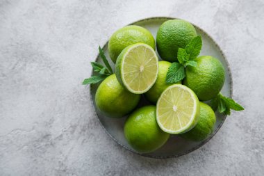 Taze nane yapraklı yeşil limonlar, beton zemin