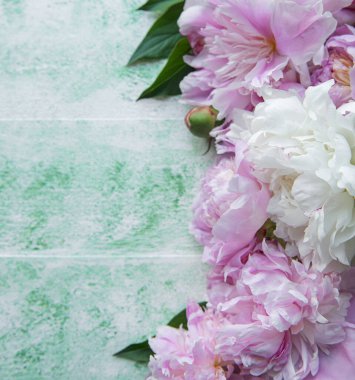 Pembe şakayıklı çiçek çerçevesi. Yeşil ahşap arka planda pembe çiçekler. Uzayı kopyala, üst görünüm. Anneler Günü, Sevgililer Günü, Doğum günü konsepti.