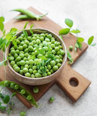 Bowl with young fresh juicy pods of green peas. Healthy organic food.  clipart