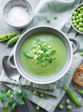 Fresh green pea soup bowl on gray concrete background