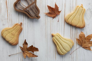 Sonbahar pastası. Balkabağı şeklinde kurabiyeler ve masada yapraklar. Samimi sonbahar konsepti.