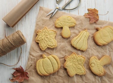 Sonbahar pastası. Balkabağı şeklinde kurabiyeler ve masada yapraklar. Samimi sonbahar konsepti.