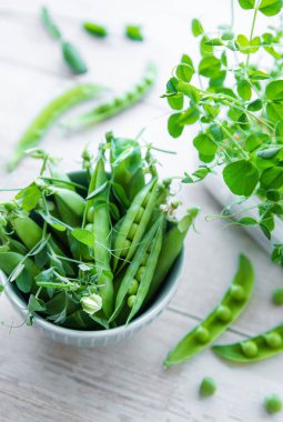 Ahşap zemin üzerinde taze taze taze bezelye kabukları olan bir kase. Sağlıklı organik gıda. 