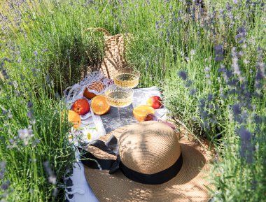 Summer picnic on a lavender field with champagne glasses and fruits