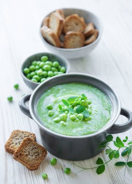 Fresh green pea soup bowl on gray concrete background