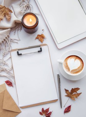 Ev işyerinde. Bir fincan kahve, tablet, yapraklar ve sıcak battaniye. Sonbahar, sonbahar konsepti. Düz yatış, üst görünüm.