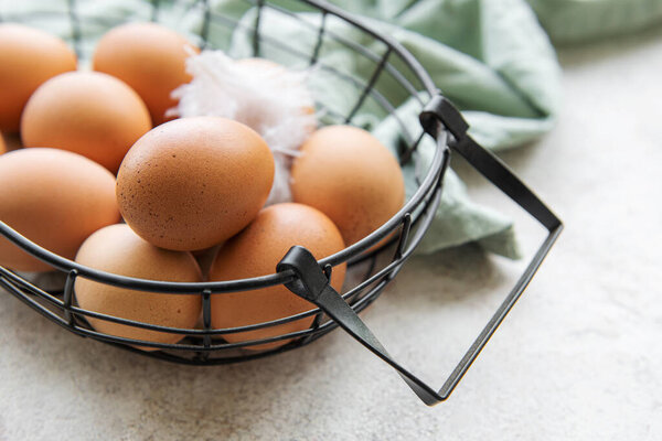 Basket of fresh brown eggs on concrete background