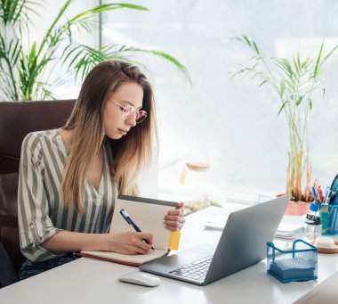 Ofisindeki bilgisayarda çalışan genç bir kadın.