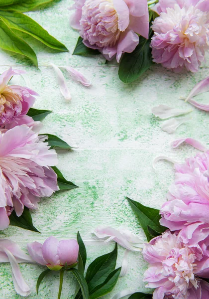 Floral frame with pink peonies. Pink flowers on a green wooden background. Copy space, top view. Mothers Day, Valentines Day, Birthday concept.