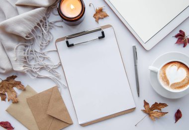 Ev işyerinde. Bir fincan kahve, tablet, yapraklar ve sıcak battaniye. Sonbahar, sonbahar konsepti. Düz yatış, üst görünüm.