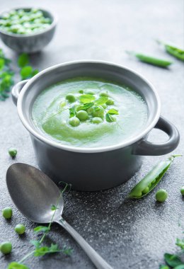 Fresh green pea soup bowl on gray concrete background