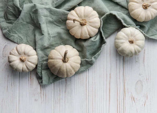 White pumpkins on a white wooden background. Festive autumn decor with pumpkins. Flat lay.