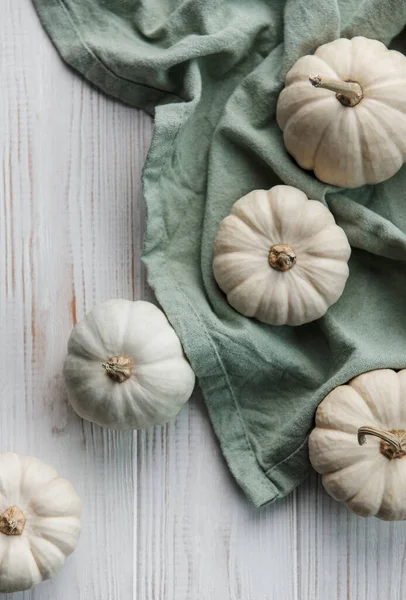 White pumpkins on a white wooden background. Festive autumn decor with pumpkins. Flat lay.