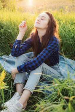 Çayırda genç ve güzel bir kadının portresi. Gün batımını seyrediyor. Yaz akşamının tadını çıkarıyor..