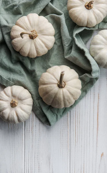 White pumpkins on a white wooden background. Festive autumn decor with pumpkins. Flat lay.