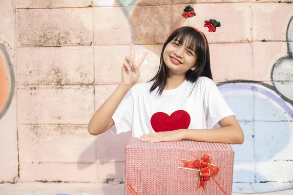 Ein Schönes Mädchen Tragen Weihnachtsmütze Halten Geschenk Auf Buntem Hintergrund — Stockfoto