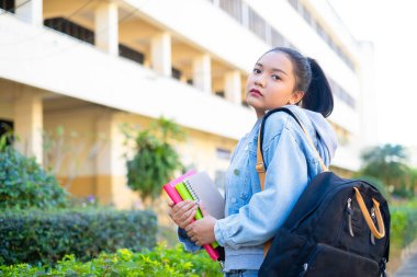 Mutlu öğrenci kız okulda kitap ve sırt çantası tutuyor, Asyalı kız..