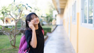 Okulda akıllı telefon kullanan güzel bir genç kız, Asyalı bir kız, turuncu bir geçmişi var..