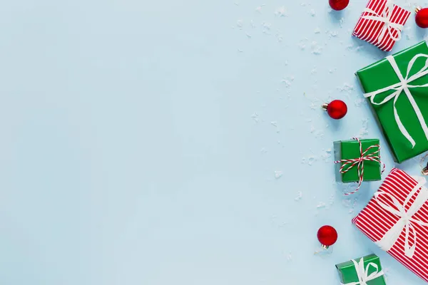 Noel ve Yeni Yıl dairesi çeşitli kırmızı, beyaz ve yeşil hediye kutularıyla üst manzaralı. Hediye kurdelesi ve ambalaj kağıdı. Kar taneleri süslemek, oyuncak toplar. Fotoğraf üzerine uzay metin alanını kopyala