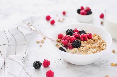 Sabah sağlıklı kahvaltı, tahıl gevreği, müsli, ahududu, böğürtlen ve gri beton masa. Sağlıklı beslenme, eko, biyolojik gıda konsepti. Gri arka planda taze lezzetli yemek. Kaliteli fotoğraf