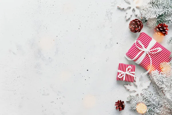 クリスマス 新年の灰色の具体的なフラットレイアウト レッドホワイトストライププレゼントギフトボックストップビュー ギフトリボンと包装紙 クリスマスツリーモミ コーン おもちゃのボール 木製の星 写真のスペースエリアをコピー — ストック写真