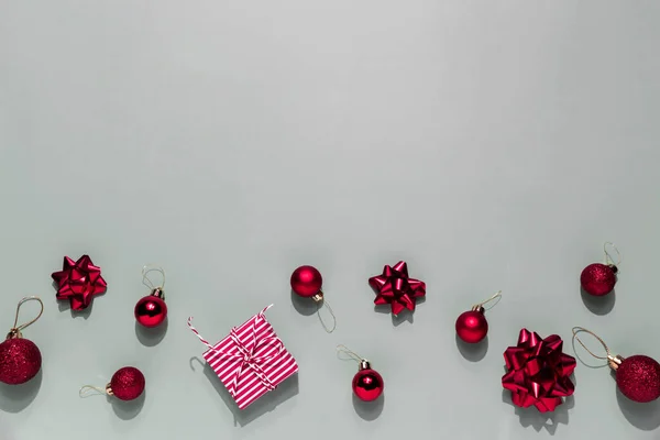 Grauer Hintergrund Mit Rosa Weihnachtsgeschenkschachtel Kleinen Roten Weihnachtskugeln Oder Kugelspielzeug — Stockfoto