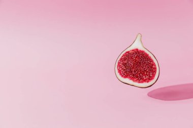 Taze lezzetli incir meyvesi yarıya indirme, pembe arka planda gölgesi var. İncir düştü ya da uçtu. Vegan çöl konsepti. Sağlıklı yemek yiyerek uçmanın gölgesi. Yüksek kalite renkli fotoğraf