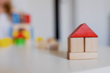 Renkli ahşap oyuncak yapı taşlarıyla oynayan kız çocuğu. Küçük bir çocuk evde ya da kreşte kule ya da ev inşa ediyor. Bebek ya da bebek için inşaat bloğu. Anaokulundaki oyun odasında karışıklık..