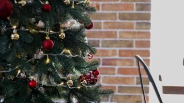 Çocuk elleri Noel ya da yılbaşı ağacını küre oyuncaklarıyla süsler. Çocuk dikkatle beyaz topu attı. Küçük bir kız Noel süslemesi takıyor, süslenmiş çelenkli köknar ağacına