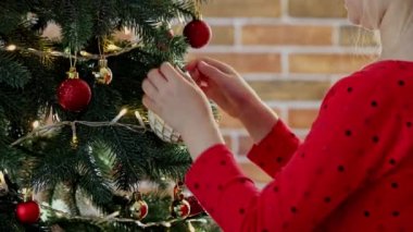 Çocuk elleri Noel ya da yılbaşı ağacını küre oyuncaklarıyla süsler. Çocuk dikkatlice doğrult ve beyaz topu at. Küçük kız Noel süslemelerini süsleyip süslüyor.
