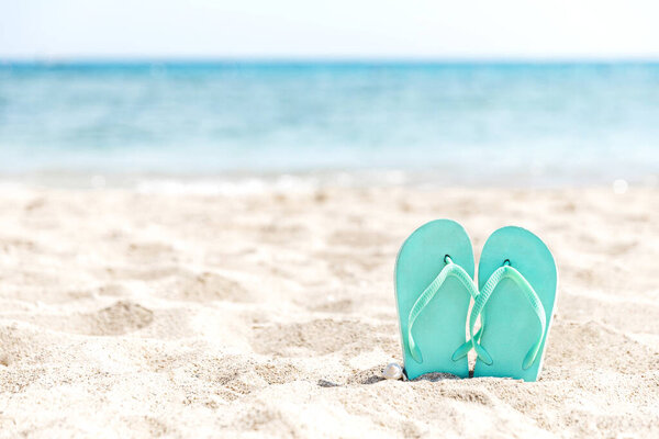 Шлепанцы, застрявшие в песке на песчаном пляже у моря или океана