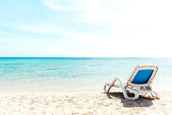 Egy magányos napozó áll a tengerparton, közvetlenül a víz mellett. — Stock Fotó