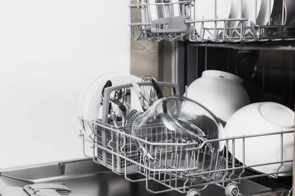 Open dishwasher with clean utensil inside, cutlery, glasses, dishes at kitchen — Stock Photo, Image