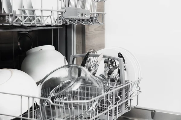 Öppen diskmaskin med ren utensil inuti, bestick, glas, rätter i köket — Stockfoto