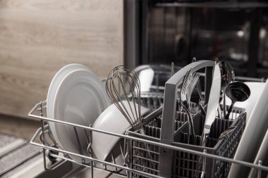 İçinde temiz aletler olan bulaşık makinesini aç. Çatal bıçak, bardak, mutfakta bulaşık.