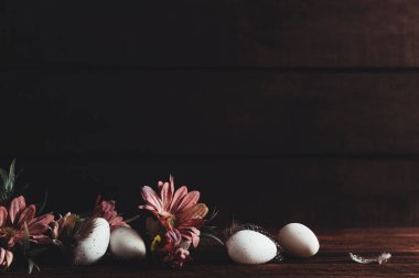 Paskalya tatili geçmişi. Paskalya yumurtaları, tahta masadaki çiçekler. Alçak tuş